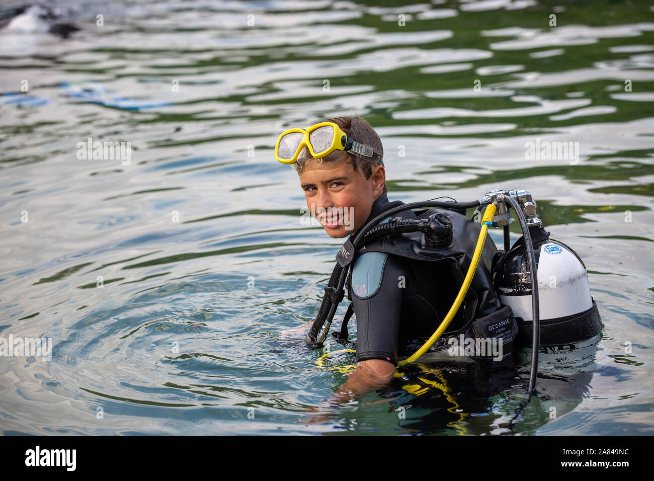 Un giovane ragazzo che indossa la piena scuba diving outfit nell'acqua. Foto Stock