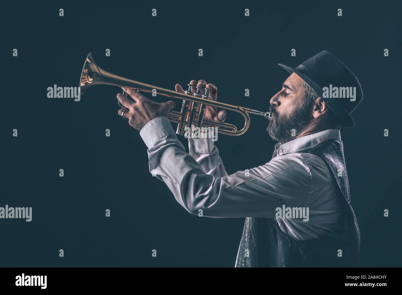 Vista di profilo di una tromba jazz player con la barba e hat.sfondo nero. Foto Stock