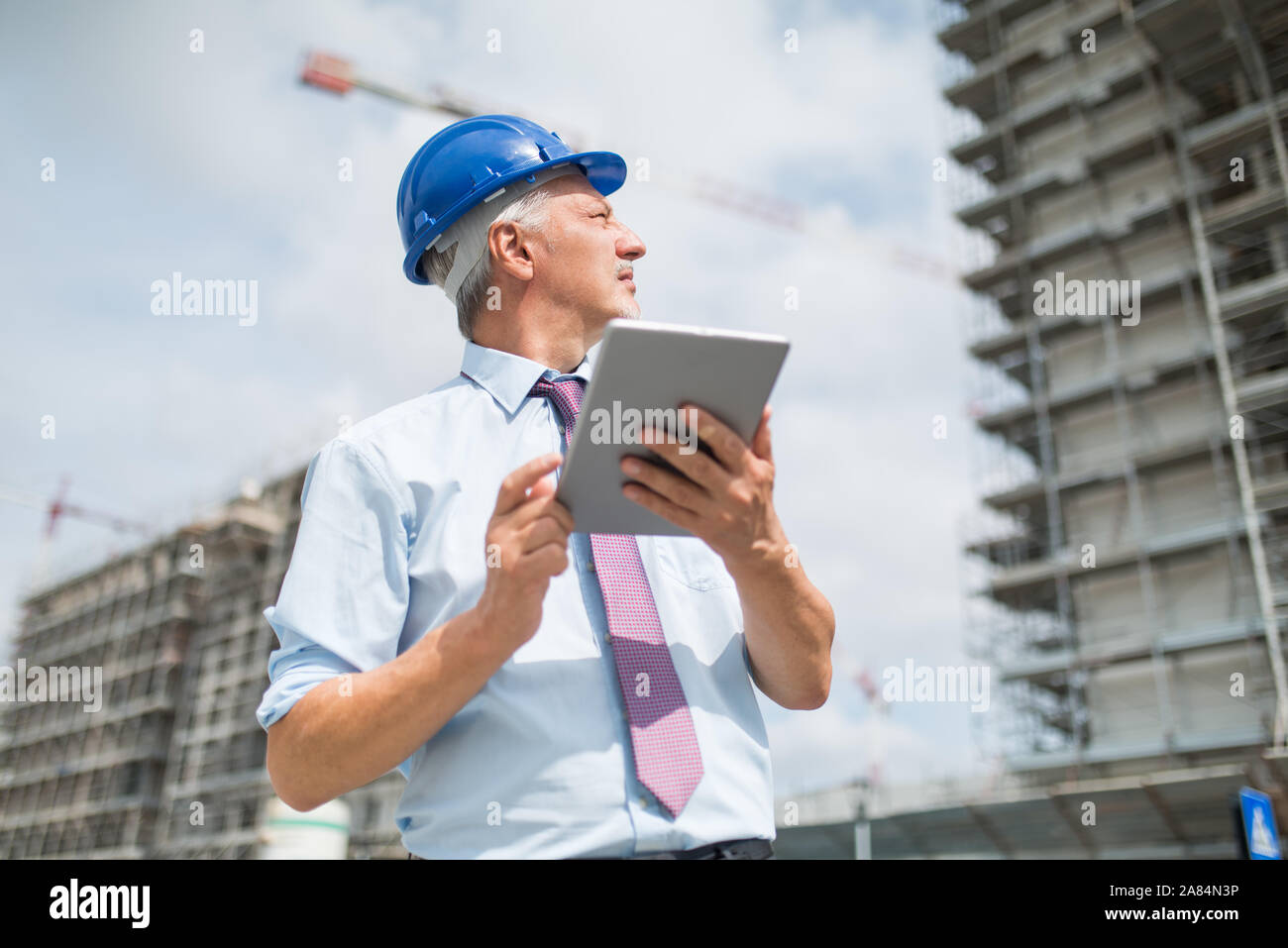Architetto utilizzando il suo tablet di fronte a un sito in costruzione Foto Stock