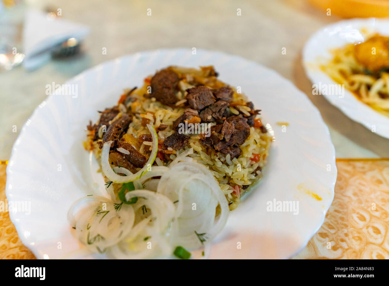 Tradizionale in Asia centrale Kazakistan Style succulento agnello Plov con cipolle su una piastra bianca Foto Stock