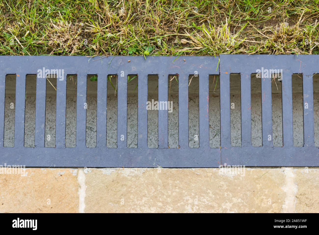 Close-up di scarico acqua grondaia che separa il prato dalla Terrazza lastricata - flatlay Foto Stock