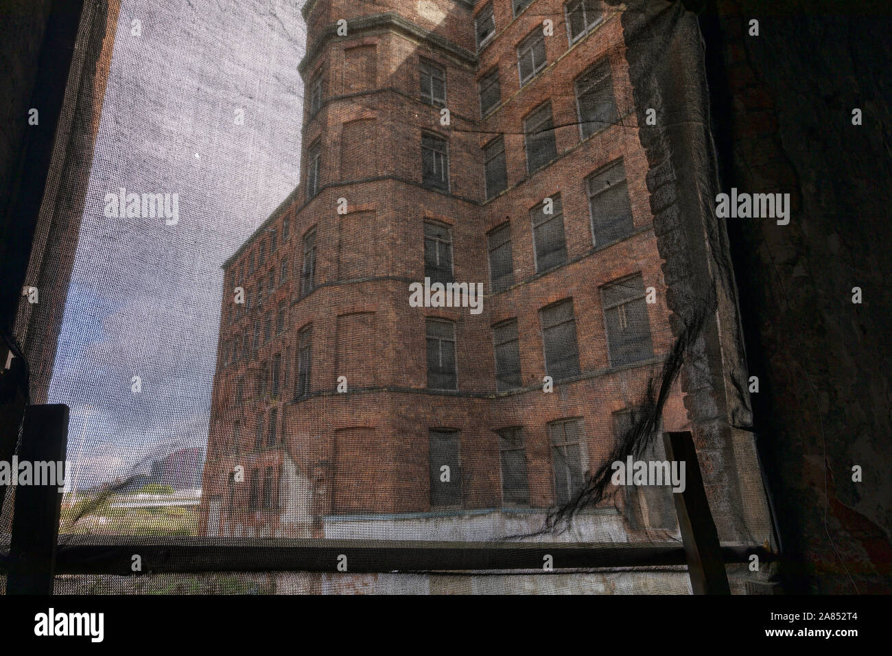 Vista attraverso la finestra del mulino abbandonato edificio che mostra una parte della struttura esterna Foto Stock