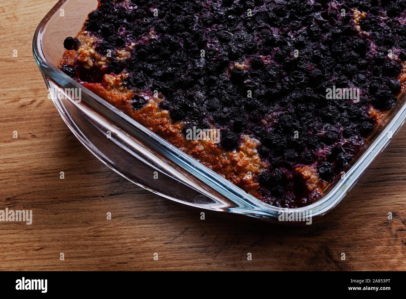 Farinata d'avena al forno con mirtilli in una padella su un legno tabella Foto Stock