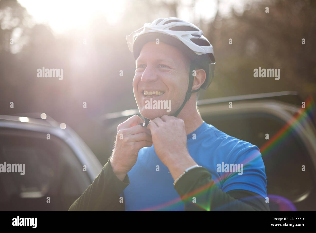Ritratto uomo sorridente fissaggio casco bici Foto Stock