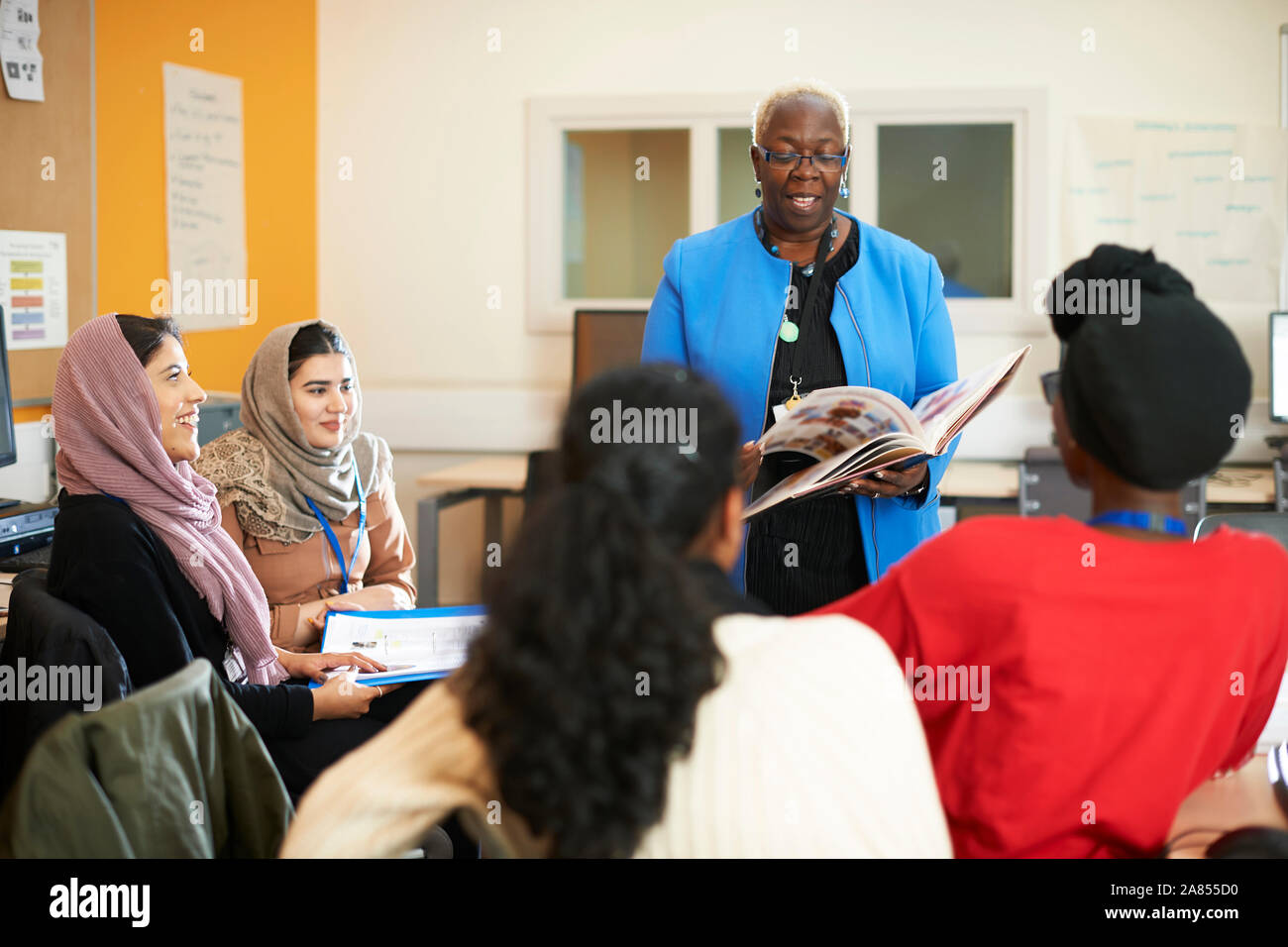 Insegnante femmina e multi-etnico gli studenti in aula Foto Stock