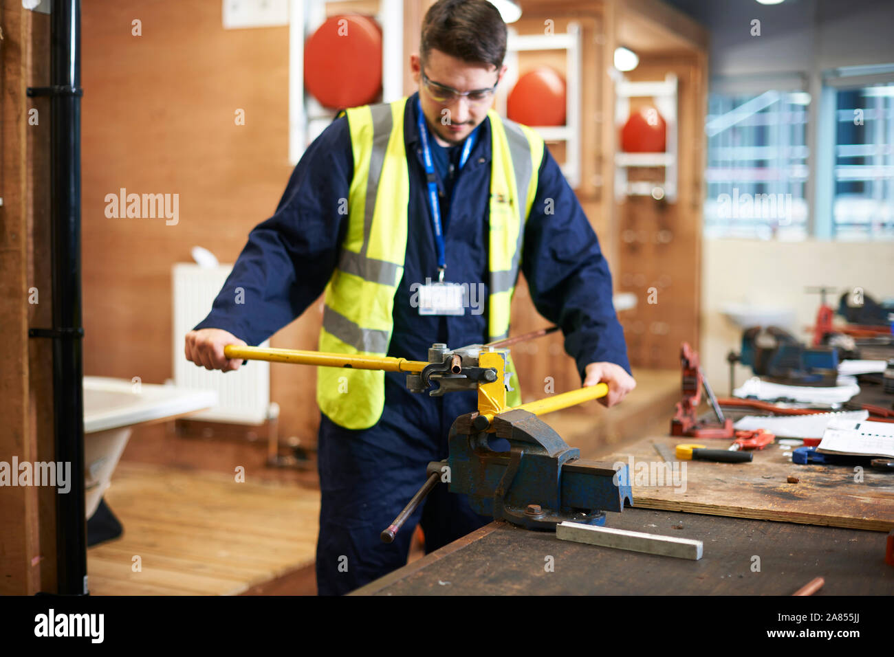 Giovane maschio studente utilizzando vise grip in negozio officina di classe Foto Stock