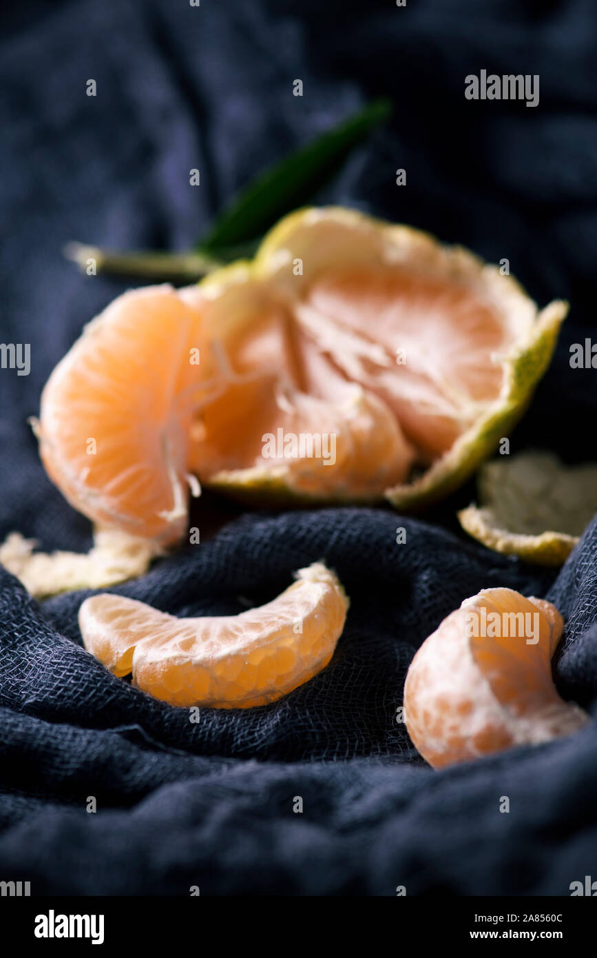 Primo piano di un pelato arancio mandarino su un grigio scuro tessuto di garza Foto Stock