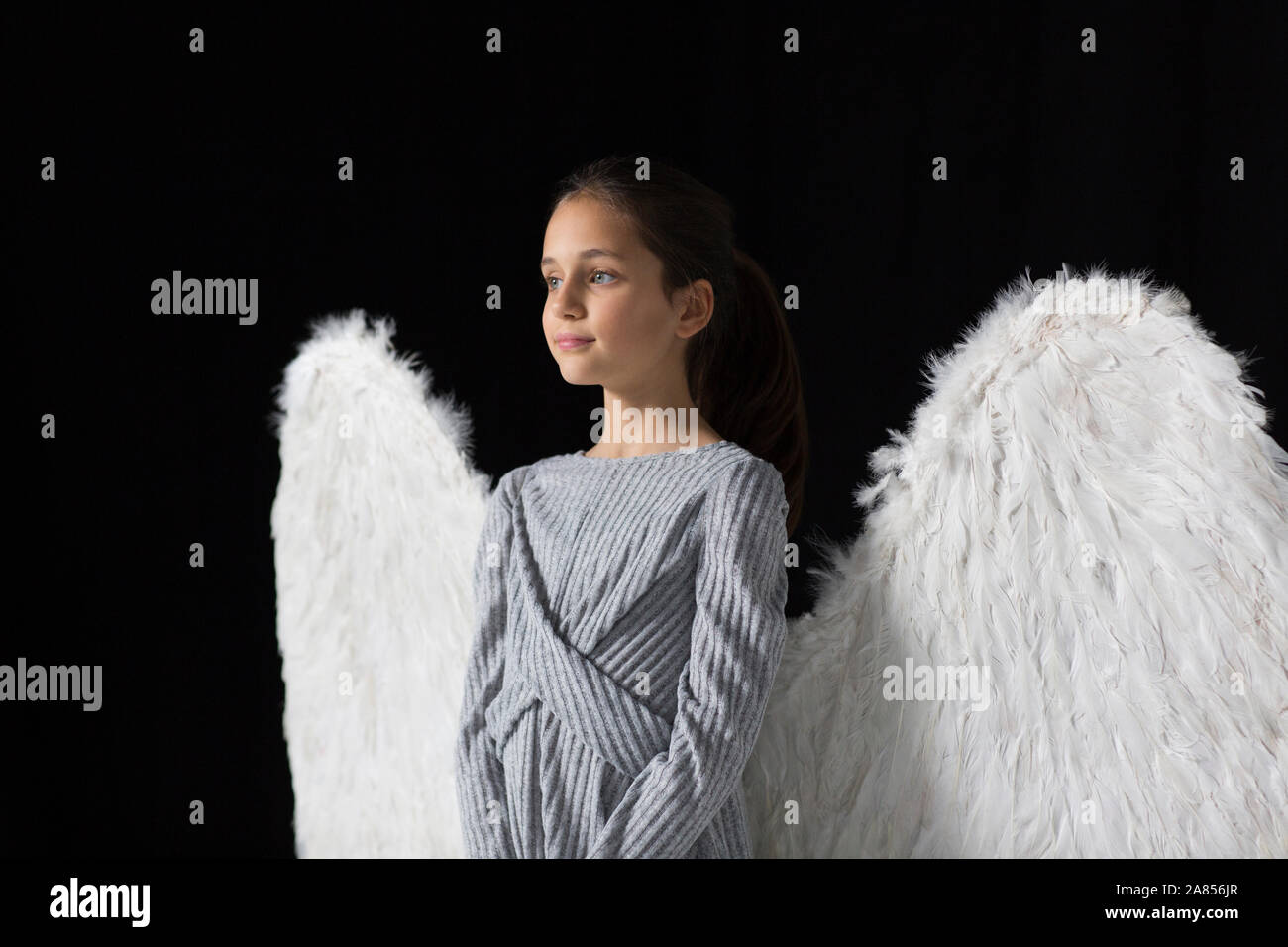 Ragazza serena indossando ali d'angelo Foto Stock