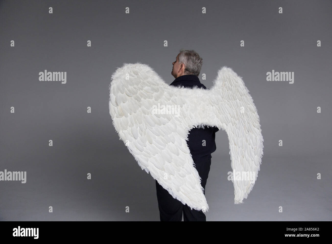 Serena uomo che indossa ali d'angelo, guardando verso l'alto Foto Stock