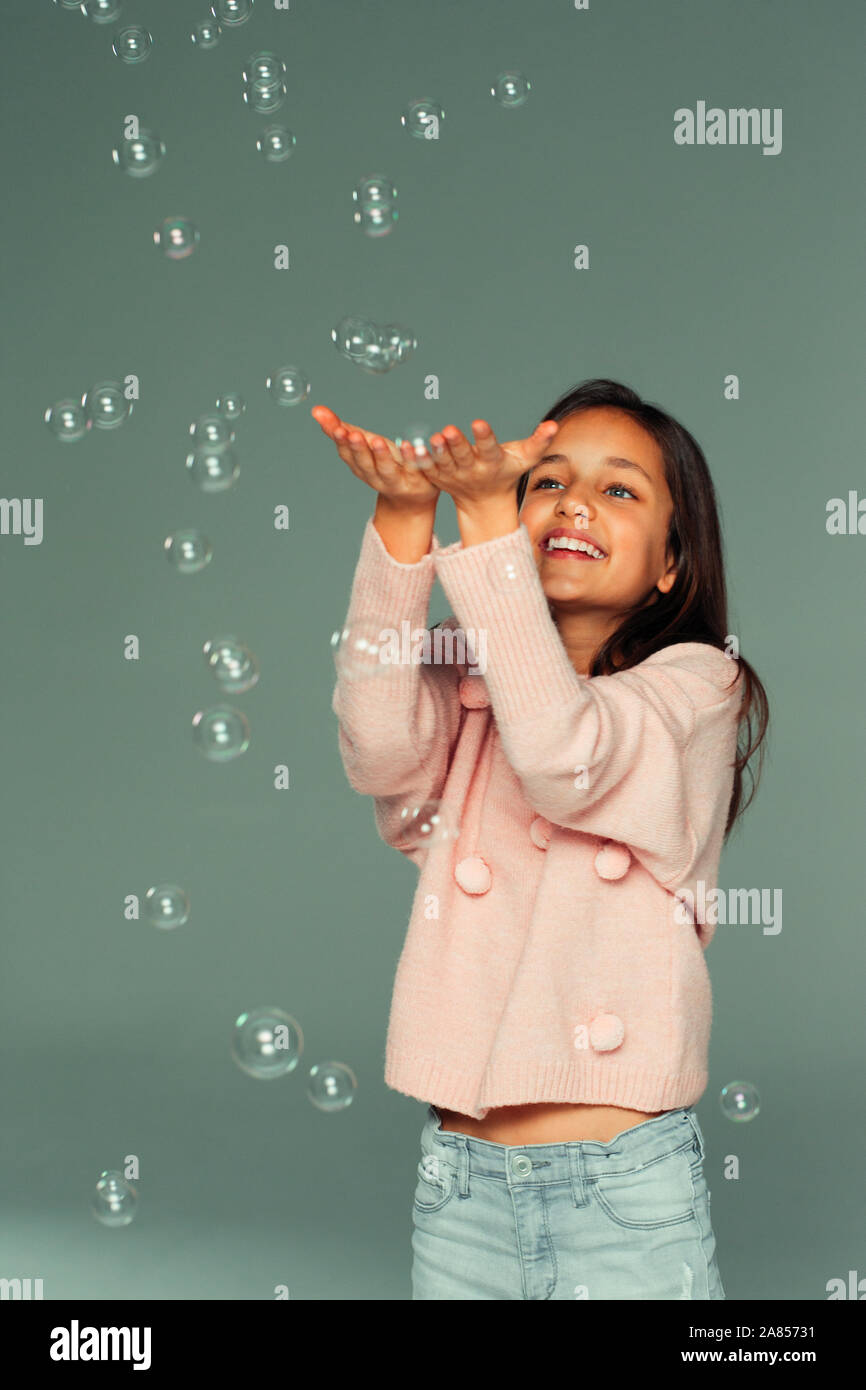 Sorridente ragazza spensierate giocando con la caduta di bolle Foto Stock