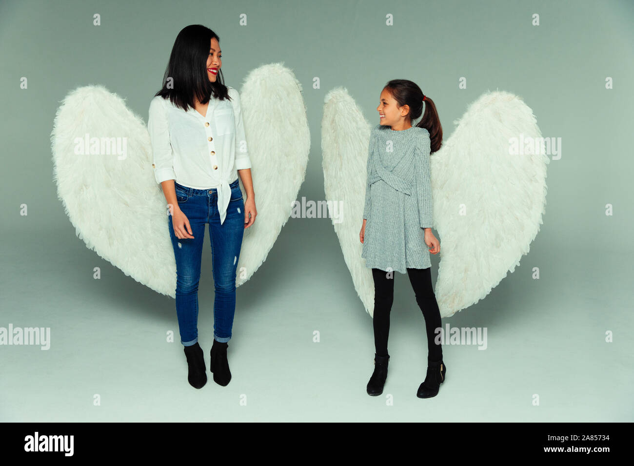 Felice madre e figlia indossando ali d'angelo Foto Stock
