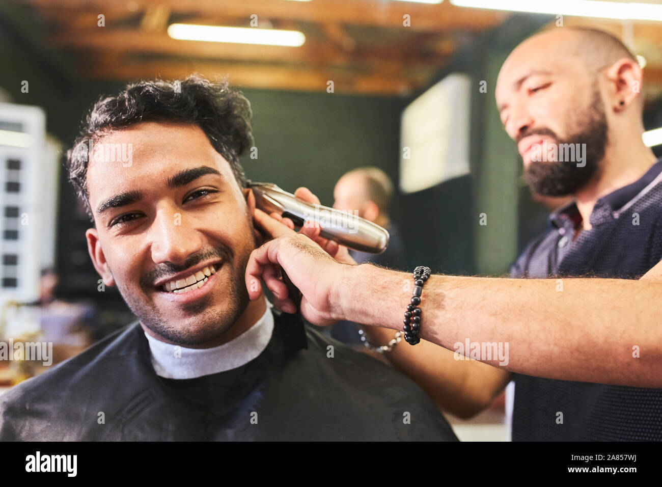 Ritratto sorridente giovane uomo taglio di capelli di ricezione al barbiere Foto Stock