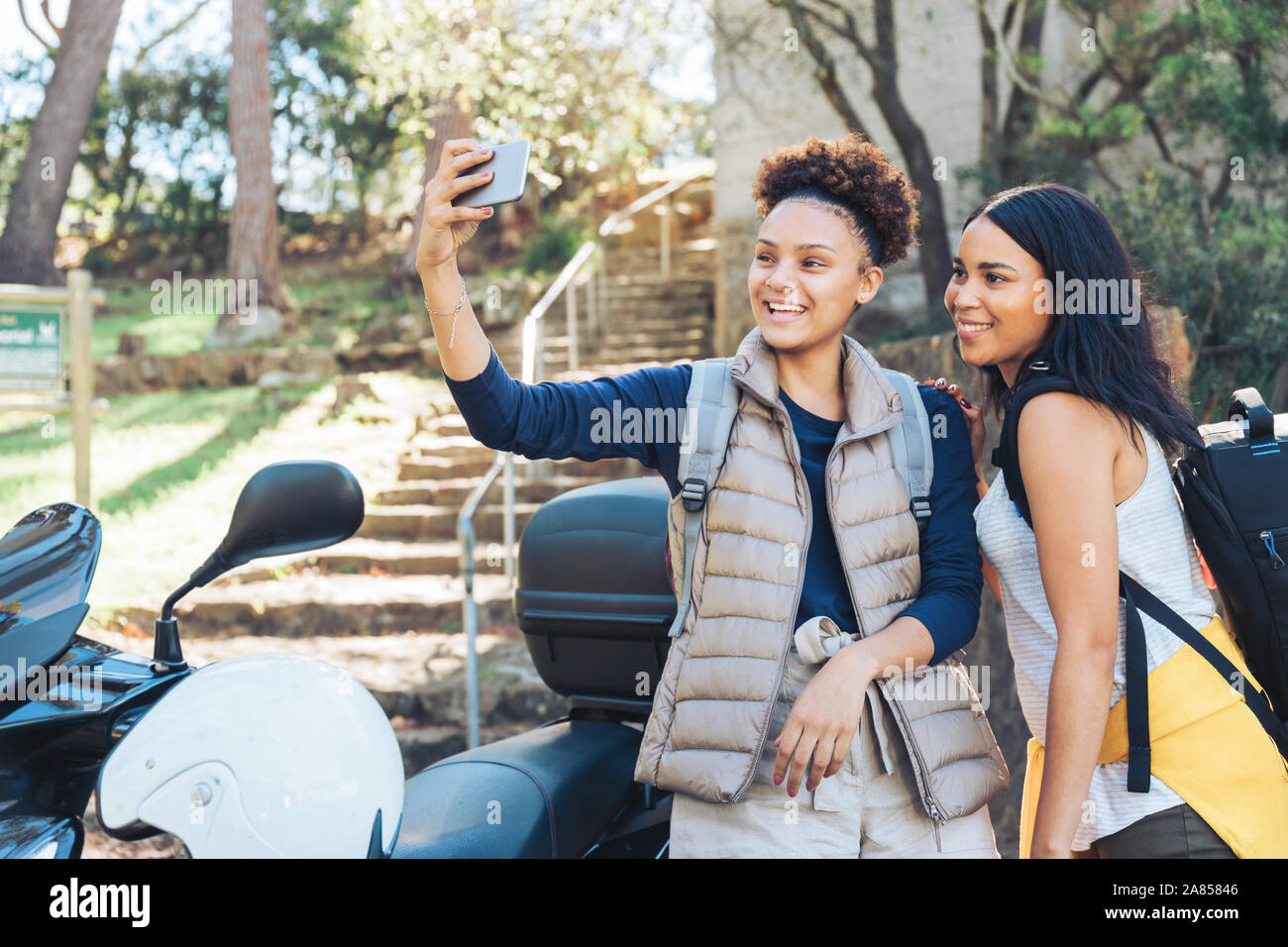 Felice di donne giovani amici prendendo selfie con la fotocamera del telefono in scooter Foto Stock