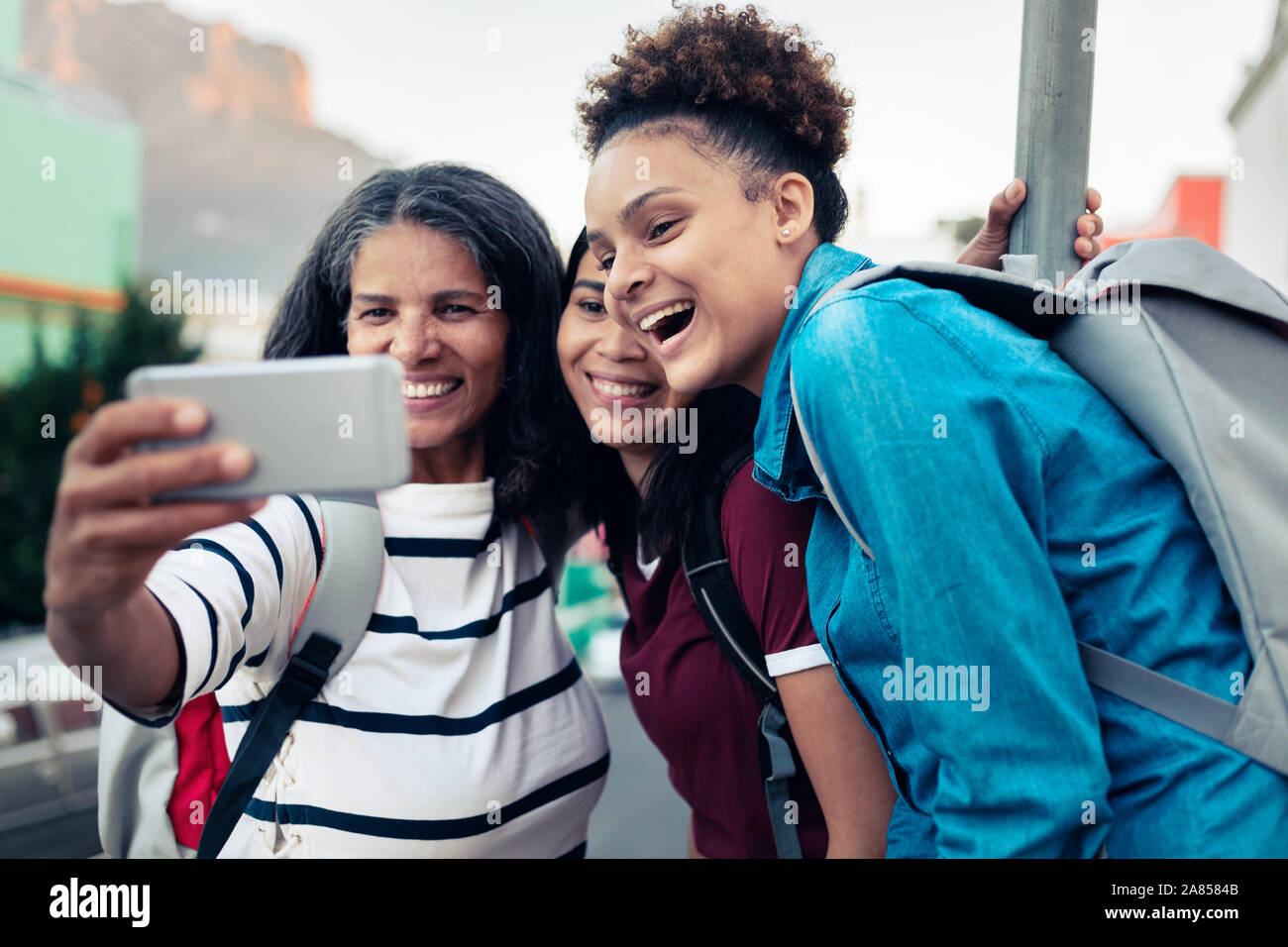 Felice la madre e le figlie backpacking, tenendo selfie con la fotocamera del telefono Foto Stock