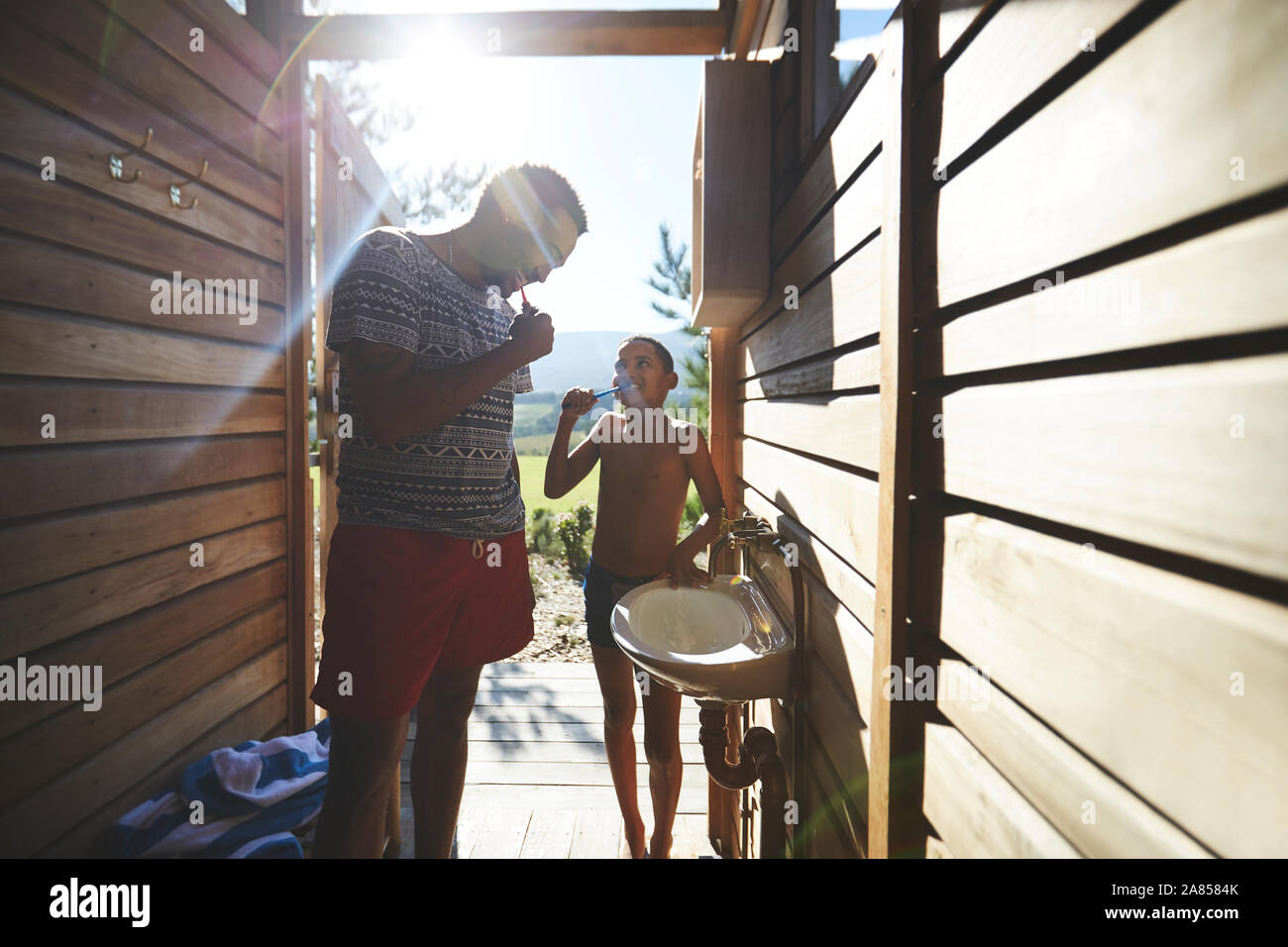 Padre e figlio di spazzolare i denti in campeggio soleggiata sala da bagno Foto Stock