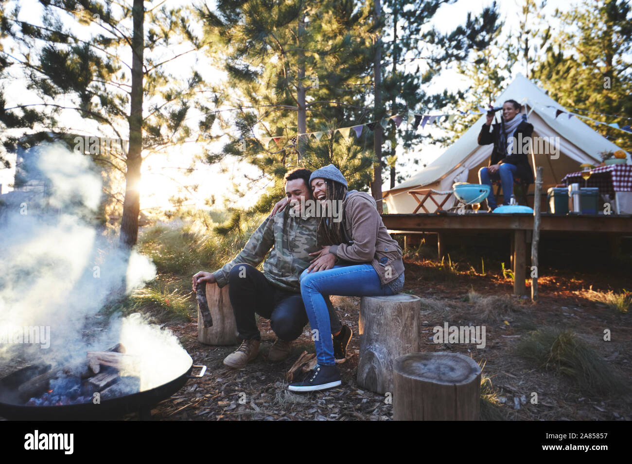 Felice coppia seduta al campeggio falò nei boschi Foto Stock