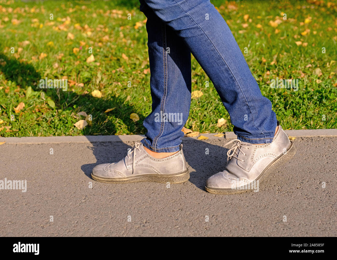 In prossimità di una donna gambe camminando in un parco d'autunno su Asphalt Trail in giornata soleggiata; uno stile di vita sano, la nozione di attività Foto Stock