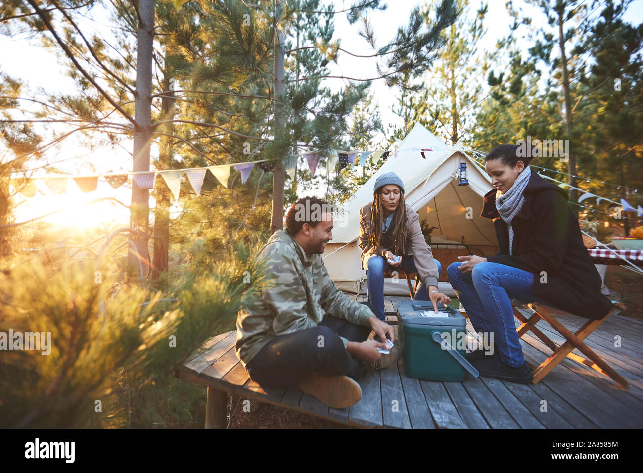 Gli amici a giocare a carte al di fuori yurta al sunny campeggio nel bosco Foto Stock