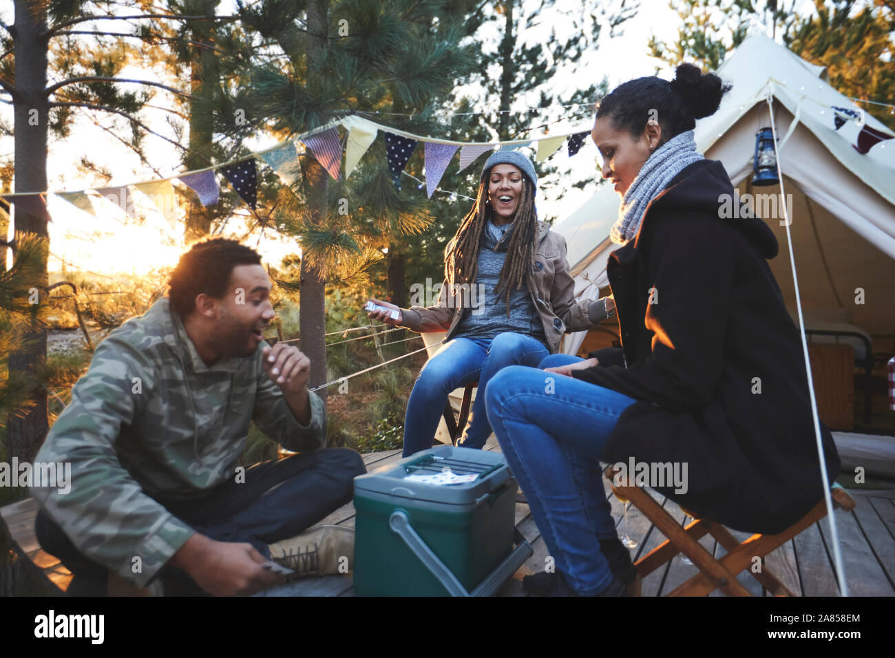 Happy amici giocando a carte al campeggio nel bosco Foto Stock