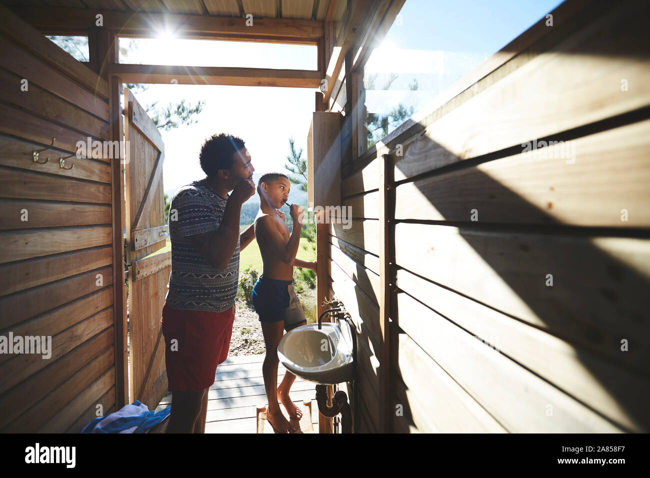 Padre e figlio di spazzolare i denti a sunny campeggio Specchio bagno Foto Stock