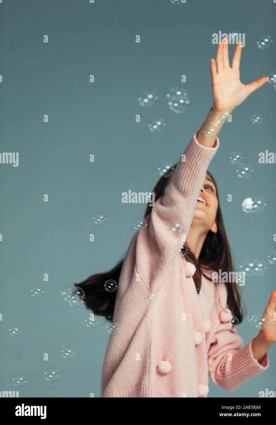 Felice, ragazza spensierate giocando, raggiungendo per la presenza di bolle d'aria Foto Stock
