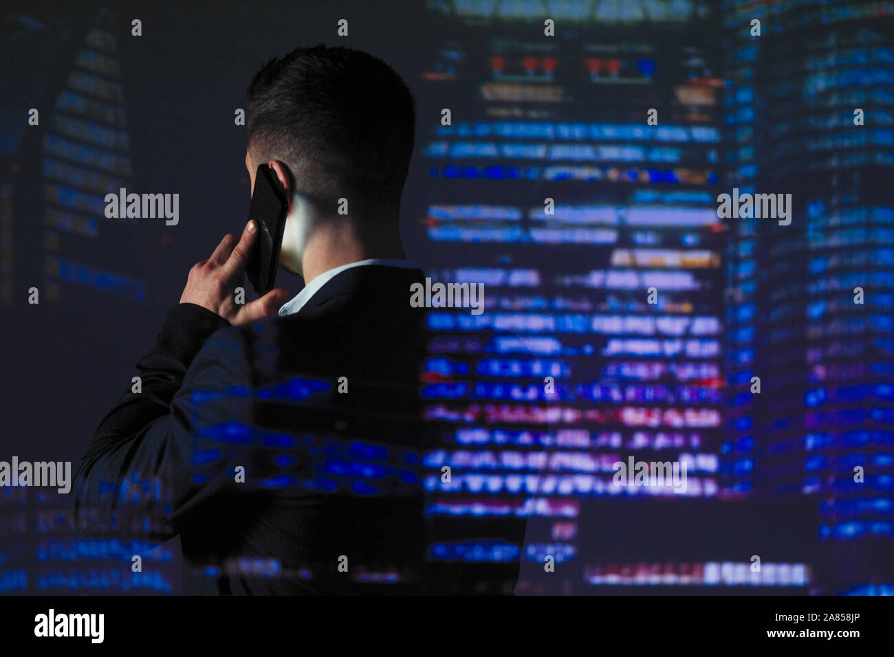 La doppia esposizione imprenditore parlando al telefono intelligente contro il grattacielo luci di notte Foto Stock