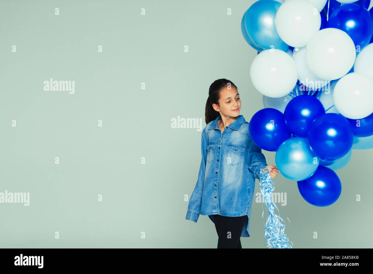 Ragazza sorridente con il blu e il bianco grappolo a palloncino Foto Stock