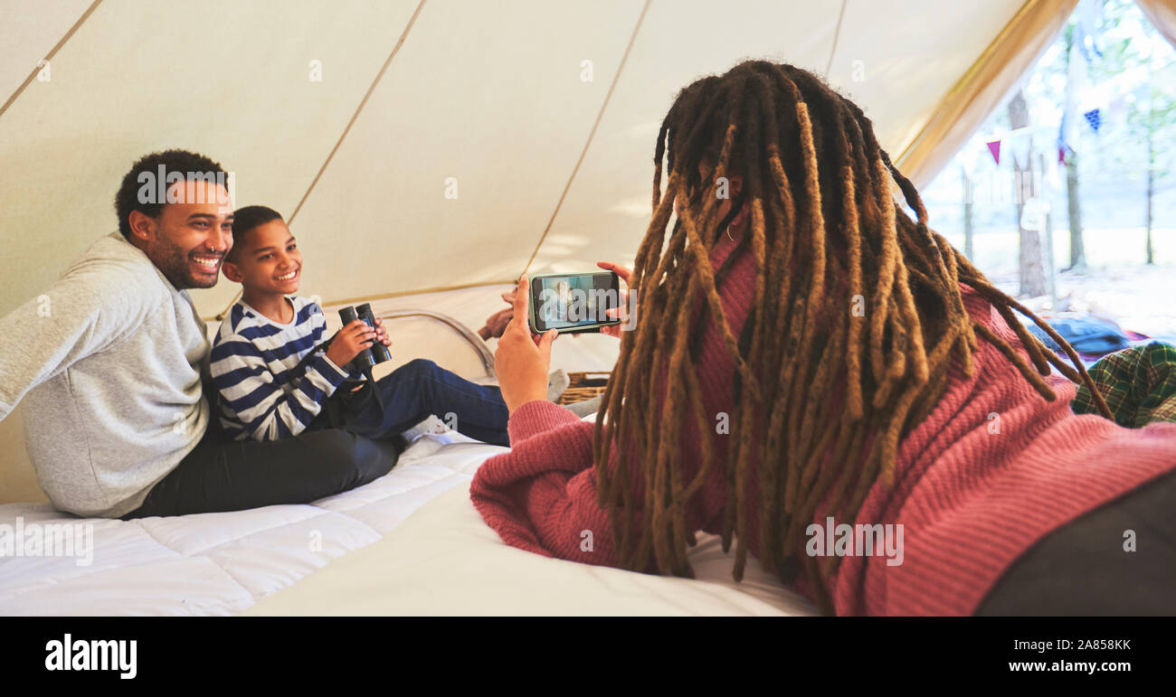 Donna con la fotocamera del telefono a fotografare il marito e il figlio in camping yurt Foto Stock