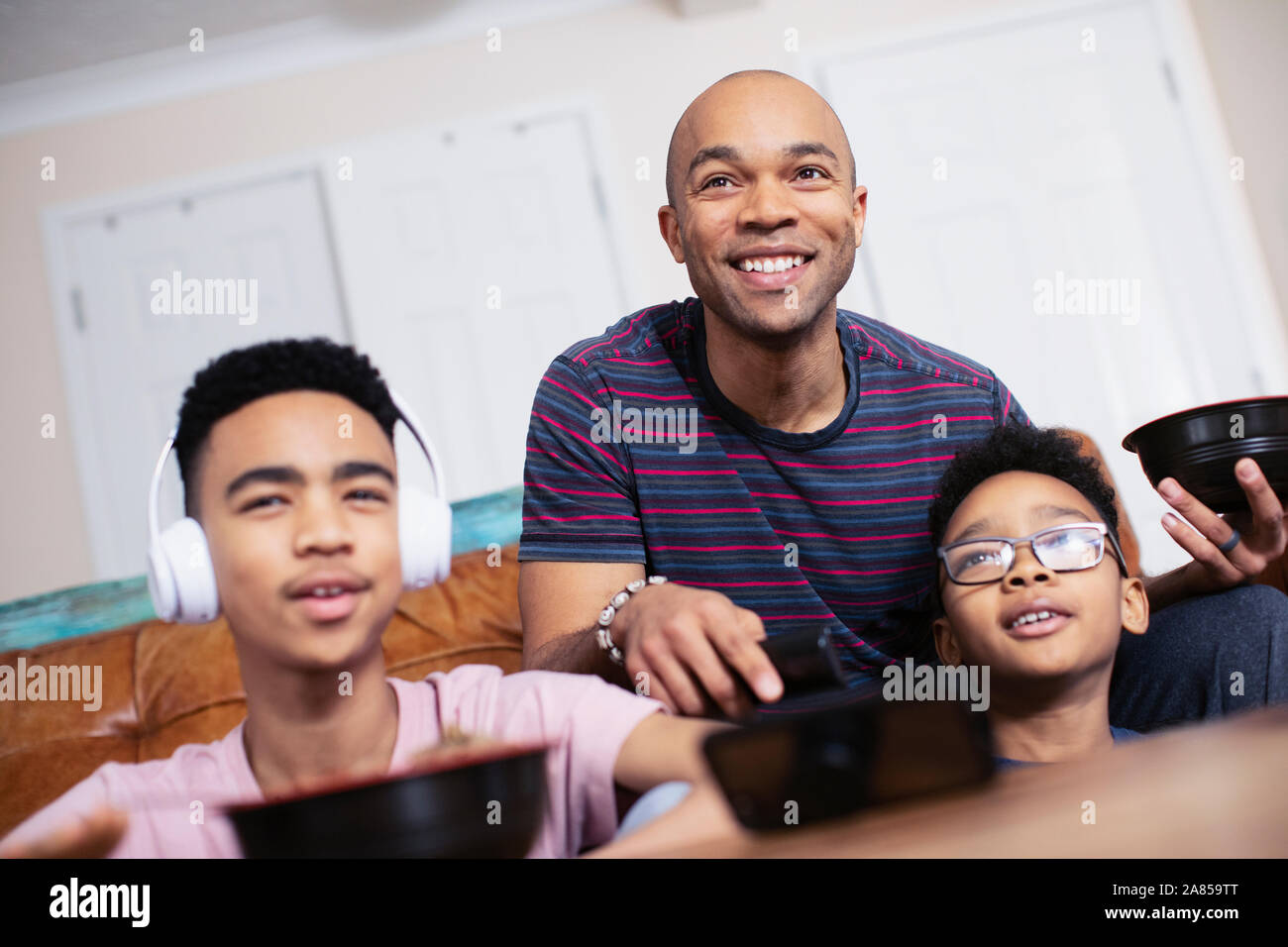 Sorridente padre e figli di mangiare e di guardare la TV Foto Stock