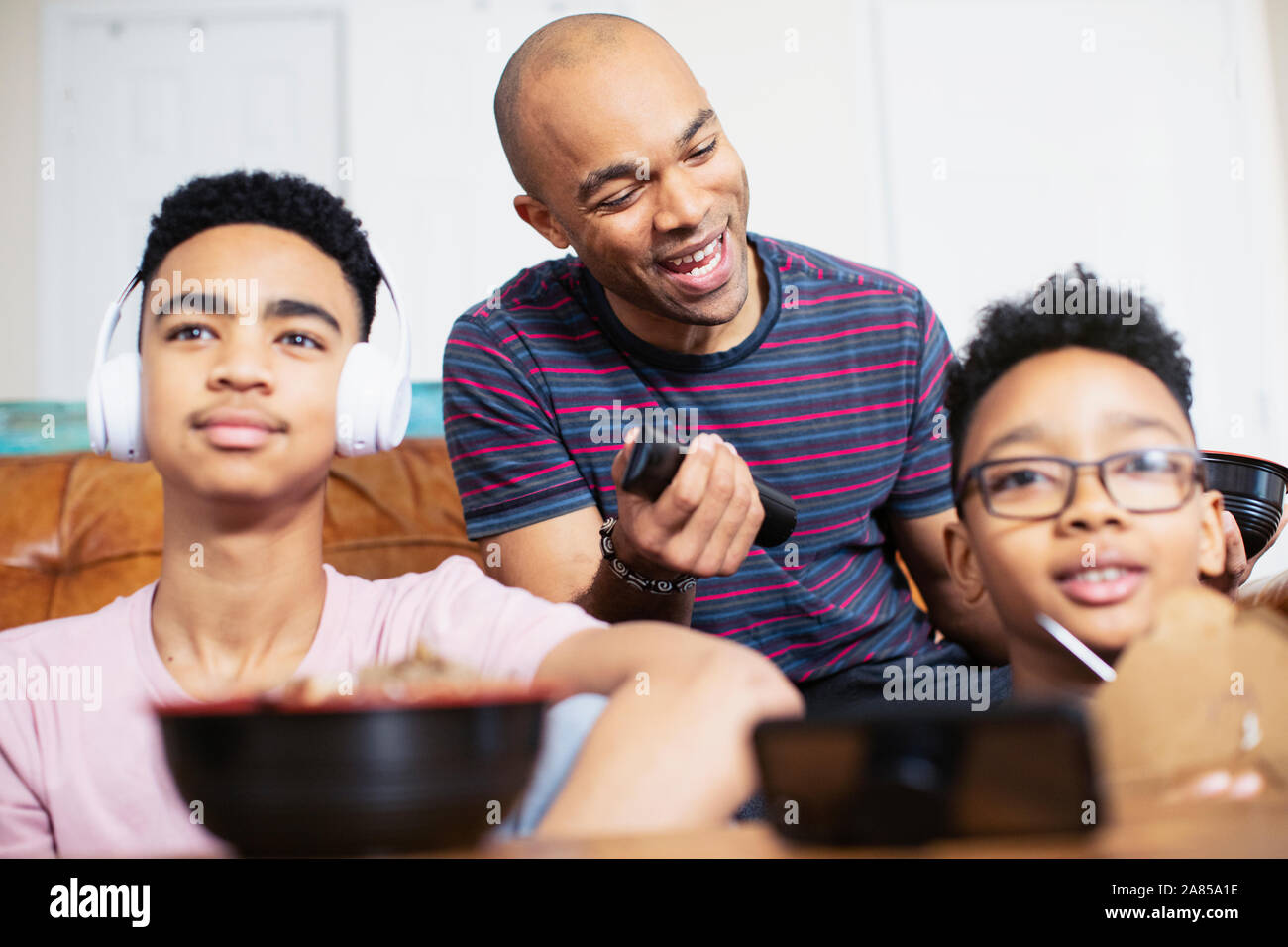 Padre e figli di mangiare e di guardare la TV Foto Stock