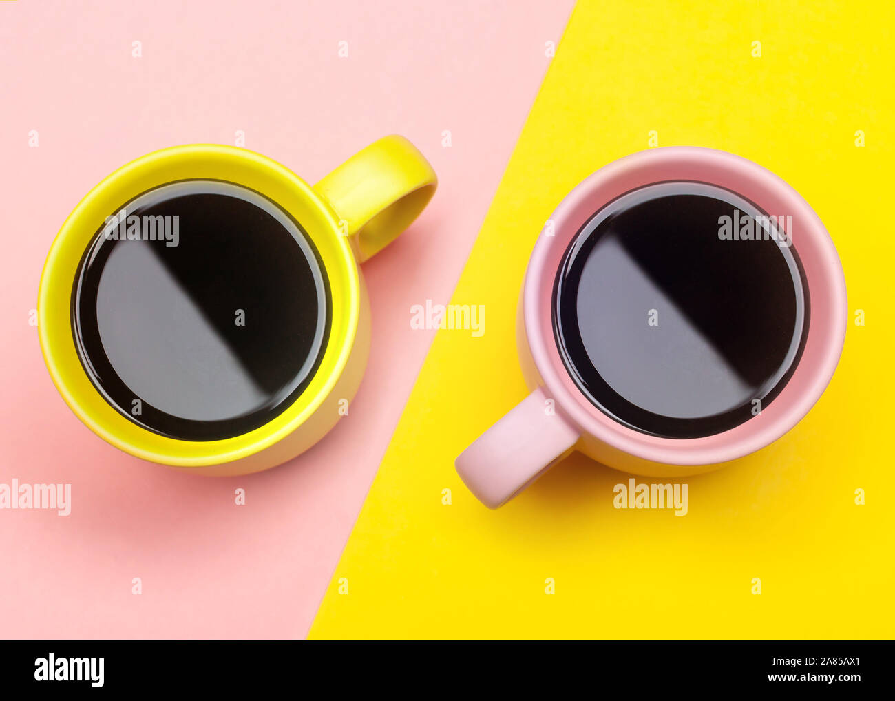 Lay piatto vista dall'alto di due tazze da caffè con rosa e giallo. Foto Stock