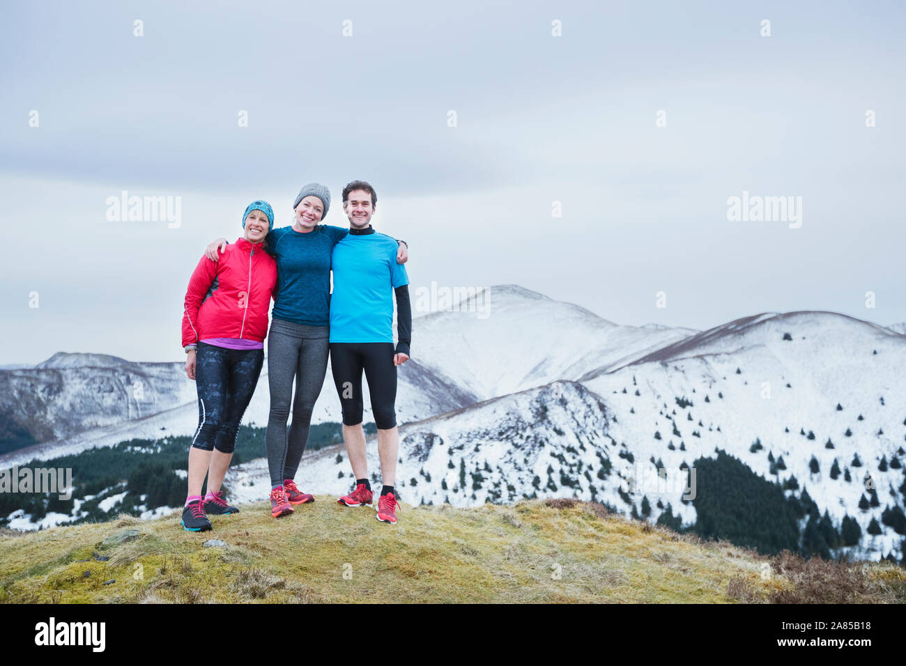 Ritratto felice famiglia escursioni sulla neve cima, Lake District, REGNO UNITO Foto Stock