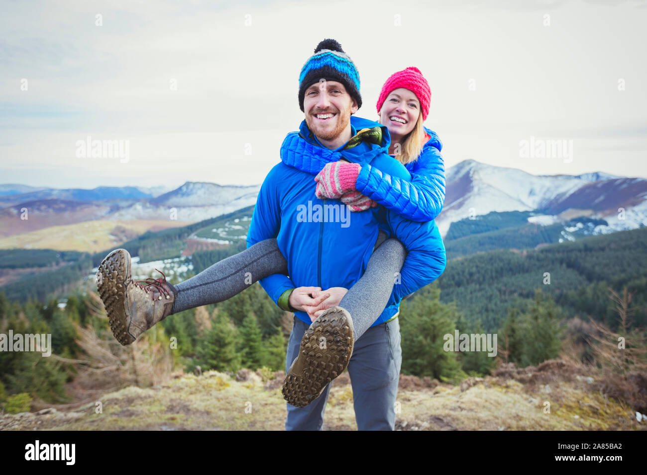 Ritratto felice coppia escursionismo, piggybacking in cima Foto Stock