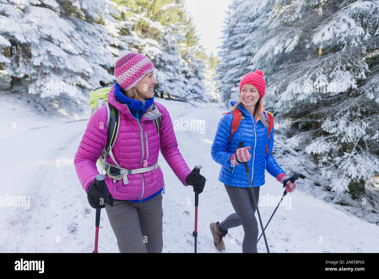 Felice madre e figlia escursionismo su terreni innevati, remote sentiero nel bosco Foto Stock