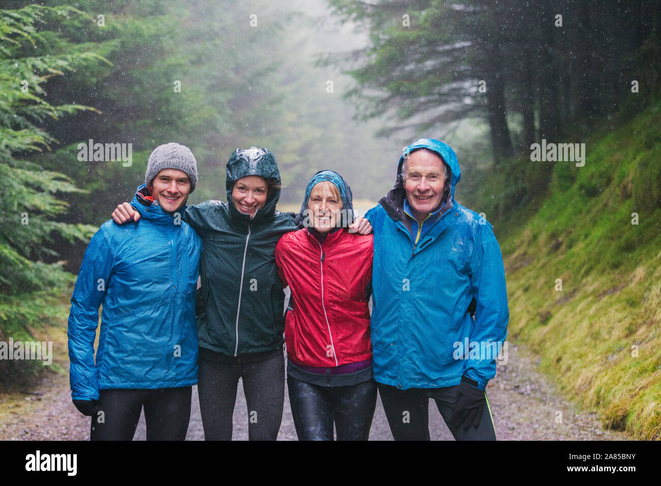 Ritratto felice famiglia escursioni nei boschi piovosi Foto Stock