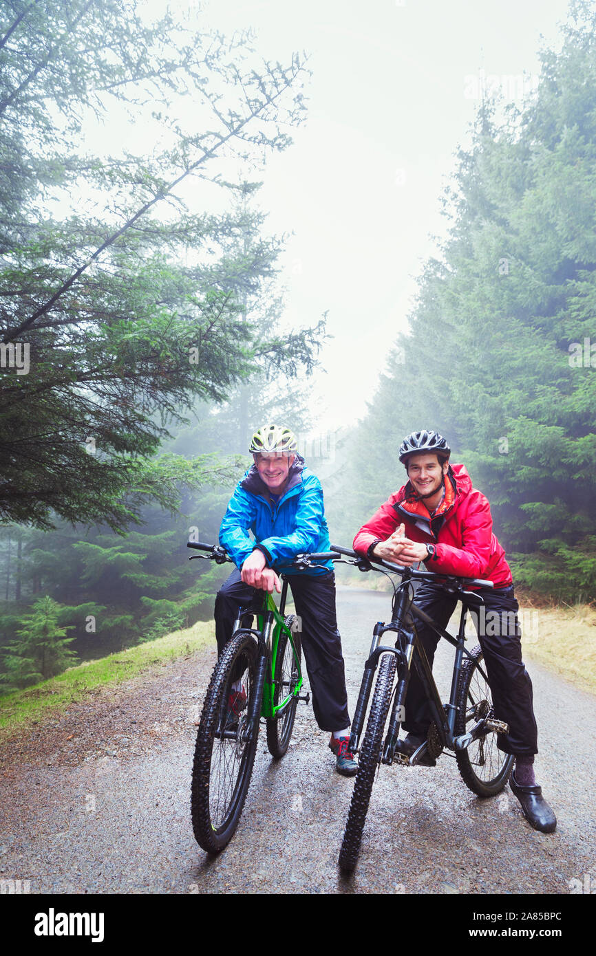Ritratto di padre e figlio in mountain bike sul sentiero nel bosco di pioggia Foto Stock