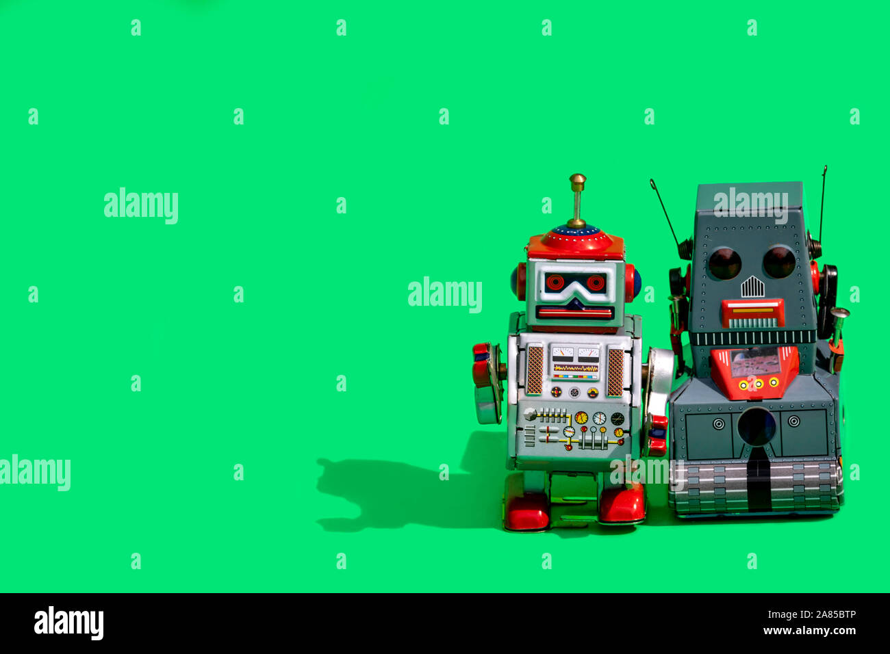 Due antichi tin toy robot su sfondo verde. Vintage e concetto classico copia libera spazio per il testo. Foto Stock