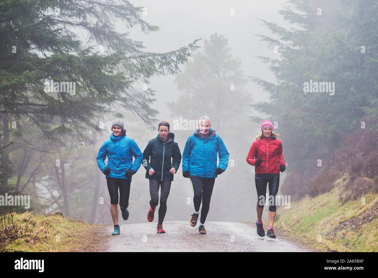 Famiglia di jogging sul sentiero nel bosco umido Foto Stock