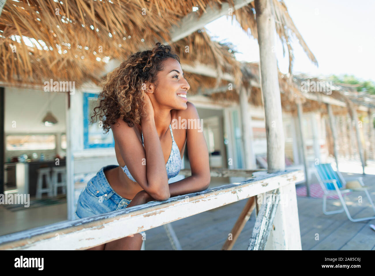 Felice e spensierato giovane donna relax su beach hut patio Foto Stock