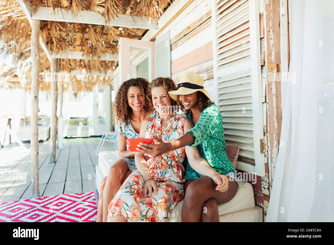 Felice madre e due figlie tenendo selfie su beach hut patio Foto Stock
