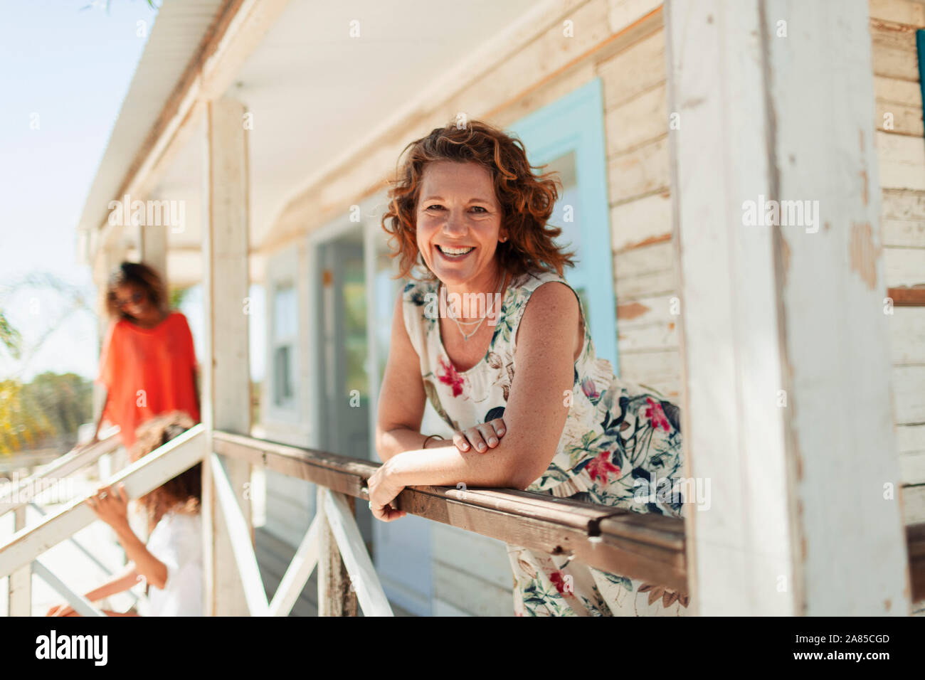Ritratto sorridente, fiducioso donna di sunny beach hut patio Foto Stock