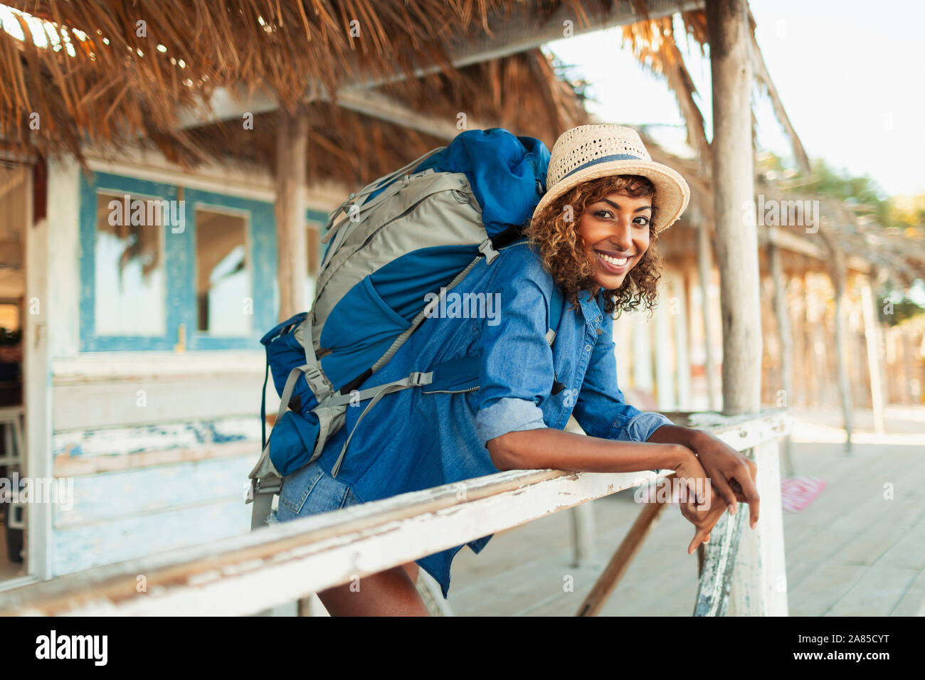 Ritratto felice giovane femmina backpacker su beach hut patio Foto Stock