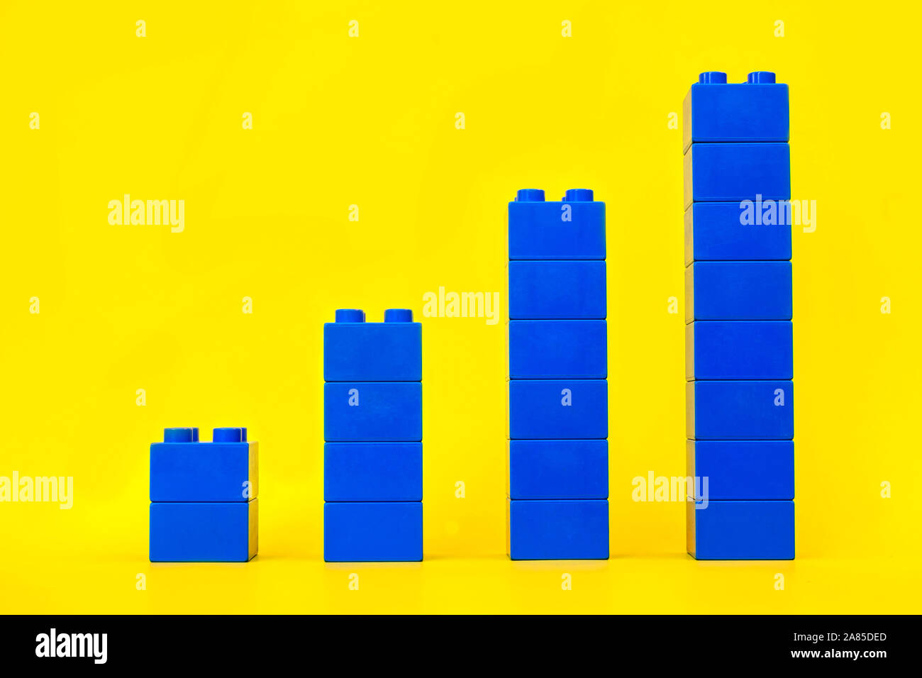 I grafici a barre in plastica blocchi di costruzione di mattoni giocattolo su sfondo giallo. Foto Stock