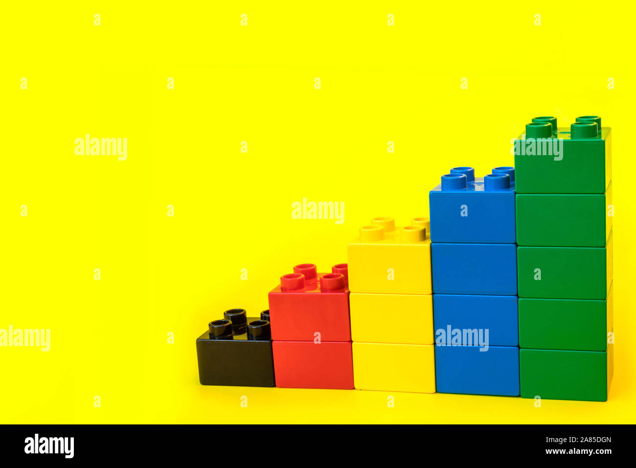 I grafici a barre in plastica blocchi di costruzione di mattoni giocattolo su sfondo giallo. Foto Stock