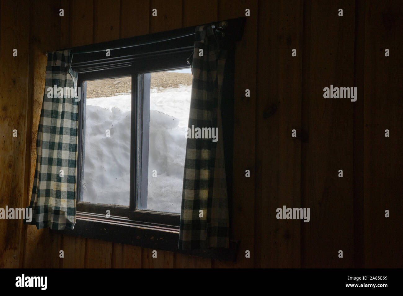 Neve imballata contro un legno cabina finestra come visto dall'interno Foto Stock
