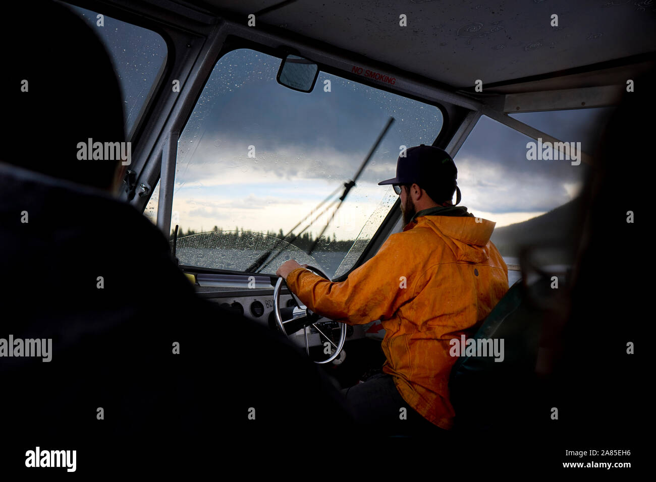 Conducente sterza un traghetto attraverso una tempesta di pioggia sul Lake Jenny Foto Stock