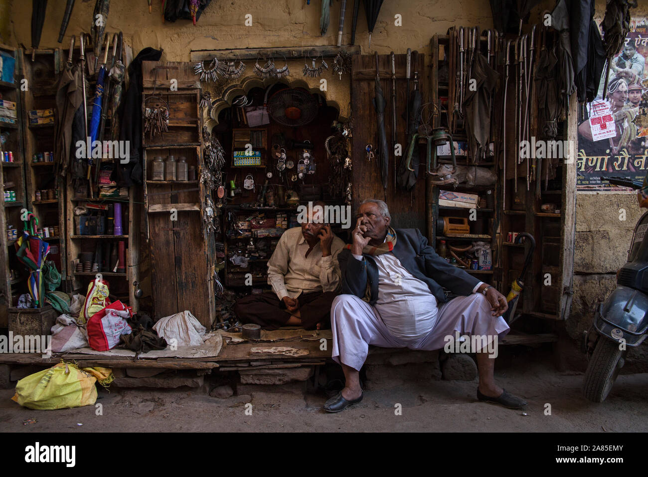 INDIA/Rajasthan/Jodhpur/Gennaio 2016: una chiave fresa e ombrello repairman chat con un amico al suo stallo, nella Città Vecchia. Foto Stock