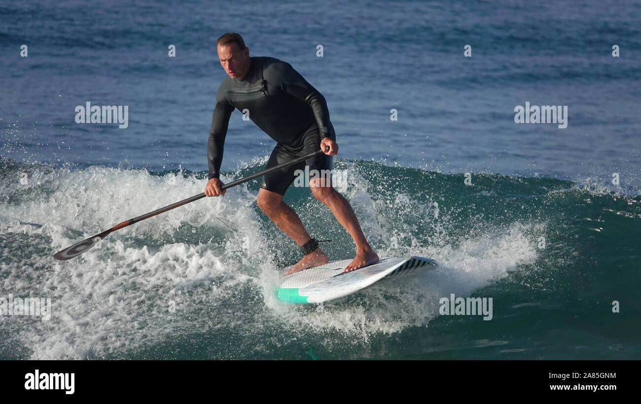 Athletic uomo (52 anno vecchio Caucasica) rimane in forma e attivi la navigazione su un SUP (Stand Up Paddle board) Foto Stock
