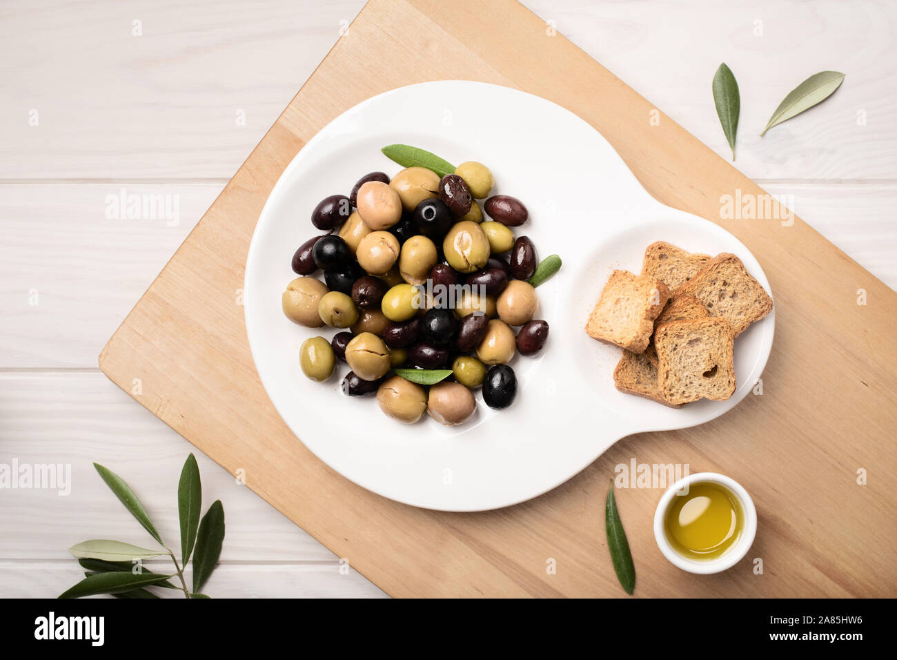 Olive marinate nella piastra su un tavolo di legno. Una gustosa cucina mediterranea. Le tapas spagnole Foto Stock