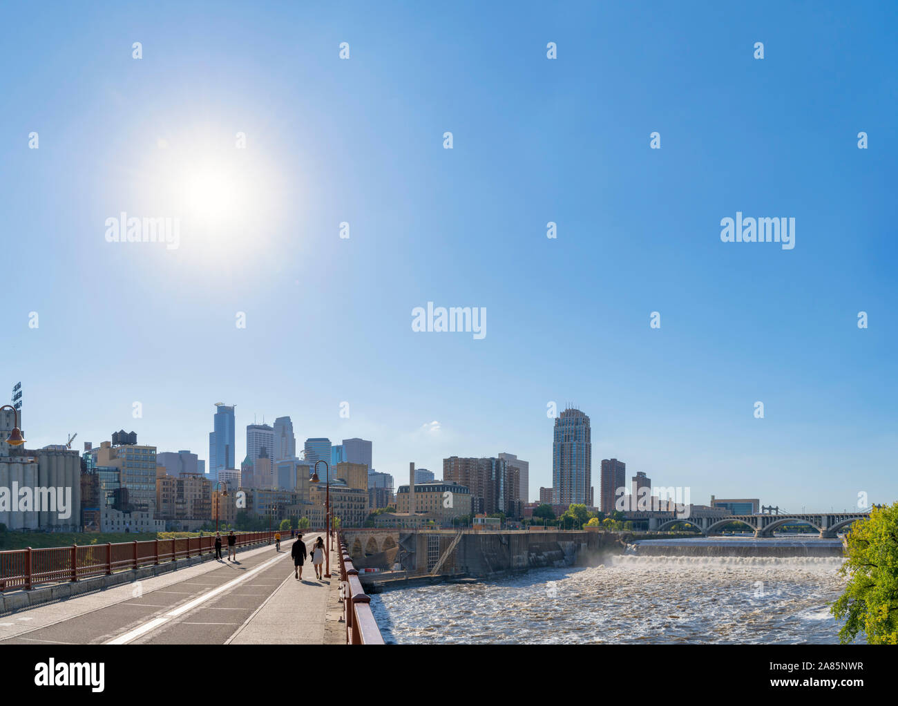 Minneapolis, MN. Lo skyline del centro cittadino dall'arco in pietra con Bridge St Anthony Falls a destra del fiume Mississippi, Minneapolis, Minnesota, Stati Uniti d'America Foto Stock